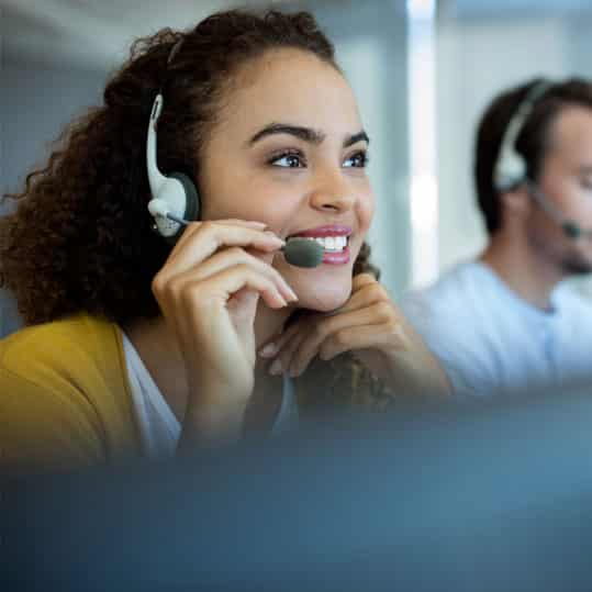 A woman working in a call center with a headset is providing a customer with service over the phone