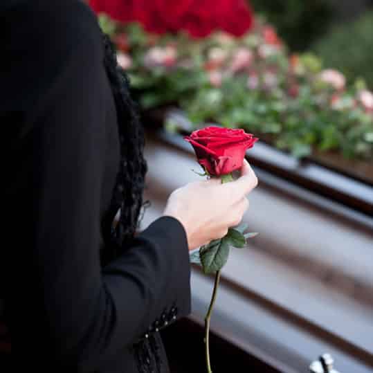 Funeral Home Answer Service Women with red rose standing next to a casket at a funeral