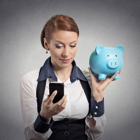 Business woman holding a piggy bank looking at her smart phone deciding if what she sees will save her more money
