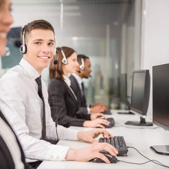 Busy call center with a male telephone answering operator smiling