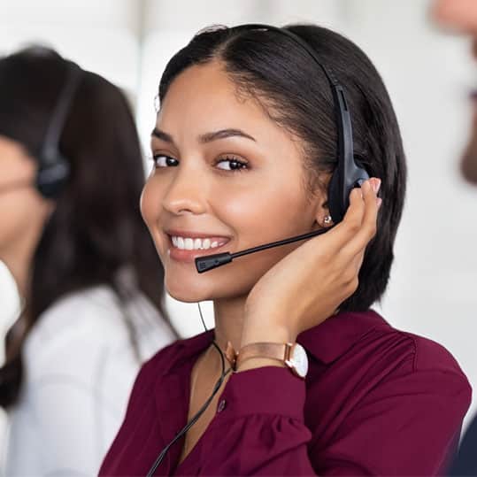 Smiling woman in a headset is about to answer a phone call that is coming in.