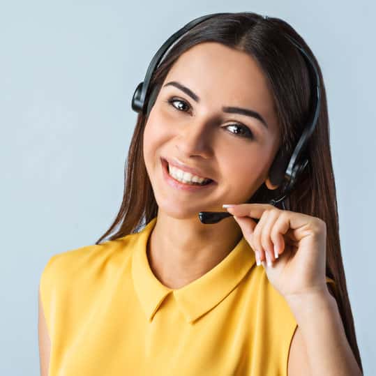 A portrait of a woman with a big smile that is a phone operator with a headset.
