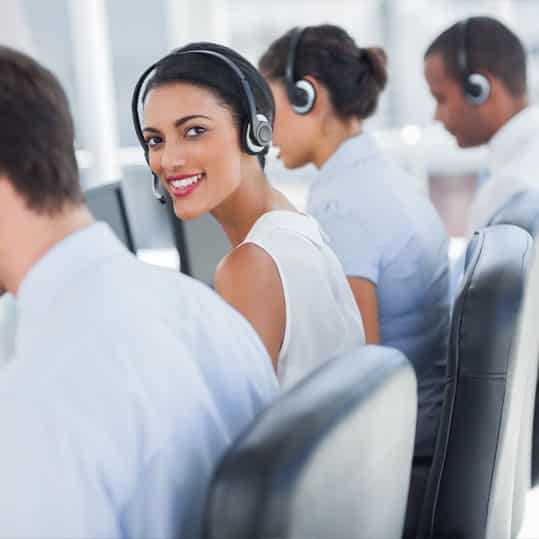 Call center employee working among her colleagues with headsets on.